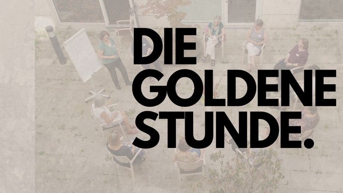 Eine Gruppe von Menschen sitzt im Freien und diskutiert.
