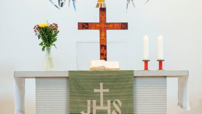 Altar in Kirche mit Kreuz, Kerzen und Blumen
