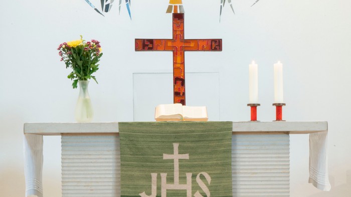 Altar in Kirche mit Kreuz, Kerzen und Blumen