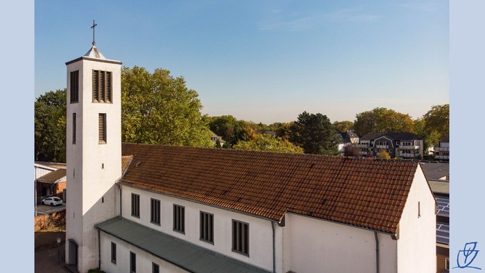 Eine weiße Kirche mit einem hohen Glockenturm und rotem Ziegeldach in einer grünen Vorstadtgegend.