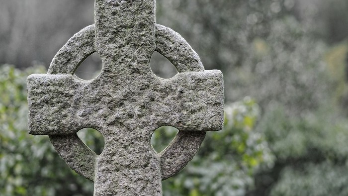 Ein steinernes Kreuz vor grünem Hintergrund