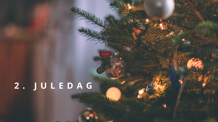 Juletræ pyntet med lys og juleting, herunder en lille julesok.