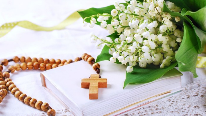 En hvid blomst og rosary på en bibel