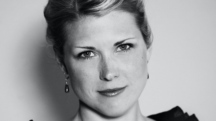 Elegant kvinde i en sort bluse med blonde i kort, stylet hår og diskrete øreringe.