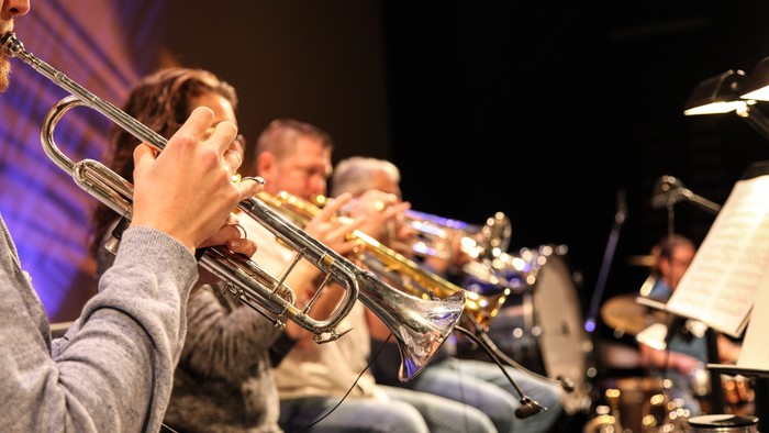 Eine Gruppe von Musikern spielt Blechblasinstrumente auf einer Bühne.
