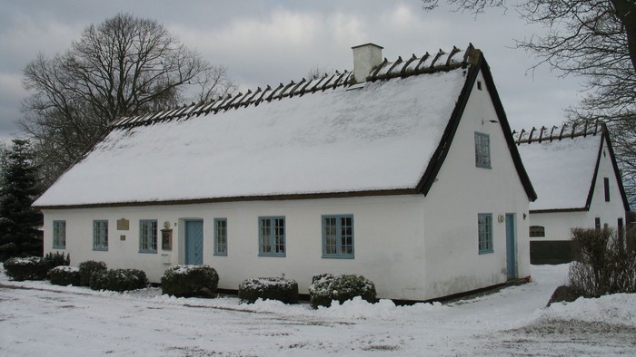En hvid og smukk landhus med taget dækket af sne