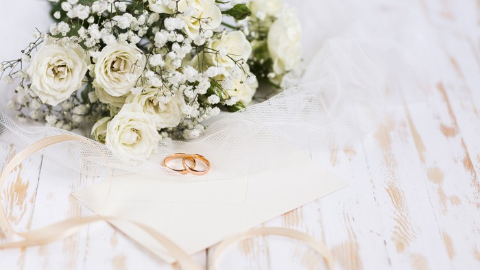 wedding bouquet next to 2 gold wedding rings