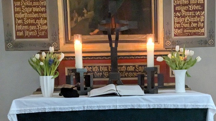 Altar mit Kreuz zwei Kerzen Blumen