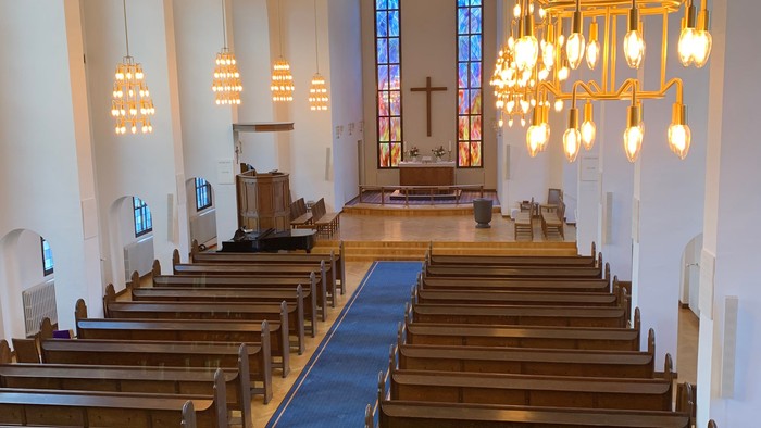 Indre del af kirke med træbænke og lysstake