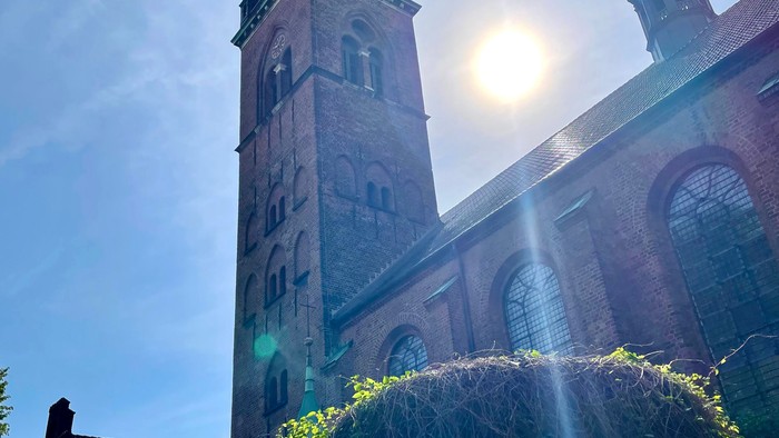 En høj kirke med to spire og solskin.