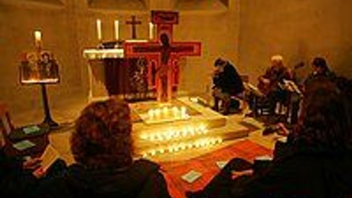 Eine Gruppe spielt Schach in einem schwach beleuchteten Raum mit Holztischen und einer kerzenbeleuchteten Atmosphäre.