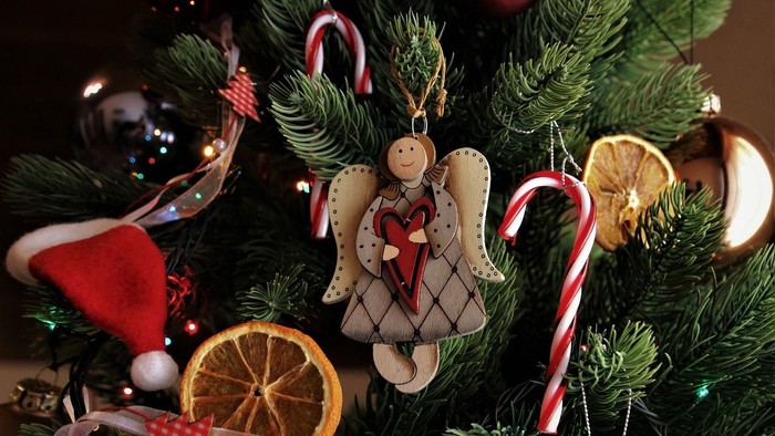 Weihnachtsbaum mit selbstgemachten Schmuckstücken, darunter ein Engel, Orangen und Zuckerstangen