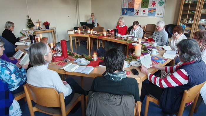 Gruppe versammelt sich um einen Tisch für ein gemeinsames Essen oder Treffen mit festlichen Dekorationen und religiösen Symbolen.