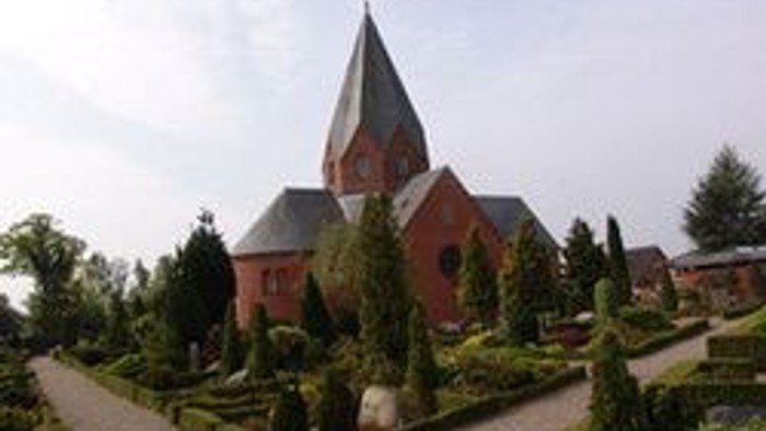 En smuk kirke med spiret og omgivelser i en park.