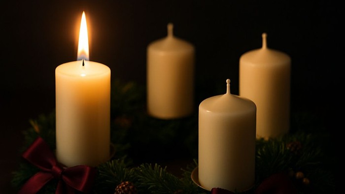 Firelyse på adventskranse med grønne grene og røde bænder
