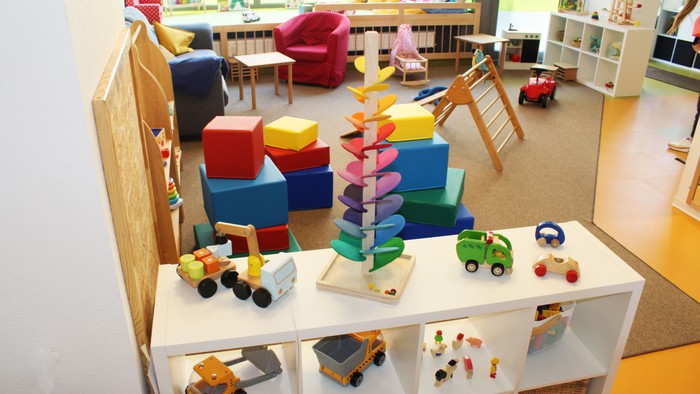 Heller Kinder-Spielbereich gefüllt mit bunten Bausteinen, Spielzeugfahrzeugen und Klettergerüsten.