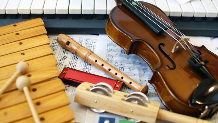 Verschiedene Musikinstrumente und ein Notenblatt auf einem Tisch arrangiert.