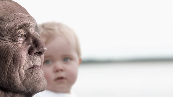 En ældre mand og et barn ser ud over vand.