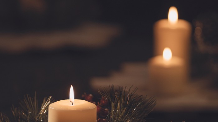 Hyggelige stearinlys omgivet af stedsegrønne krans og festlige dekorationer skaber en hyggelig julestemning.