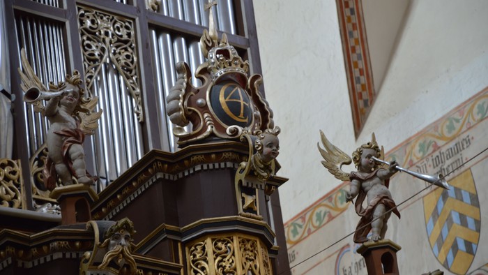 Komplekst orgel med udsmykkede udskæringer og englefigurer i et historisk kirkeinteriør.