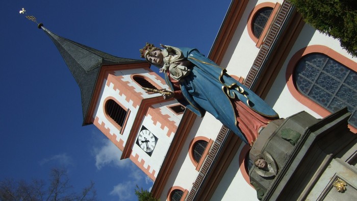 Statue auf einer farbenfrohen Kirche mit verziertem Turm und dekorativen architektonischen Details.