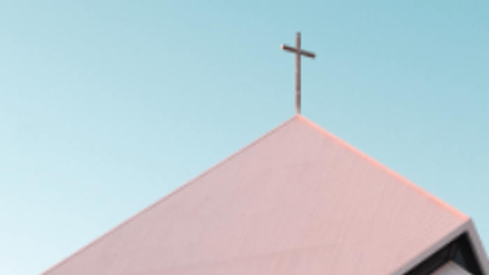 Ein rosa Gebäude mit einem Kreuz darauf vor blauem Himmel