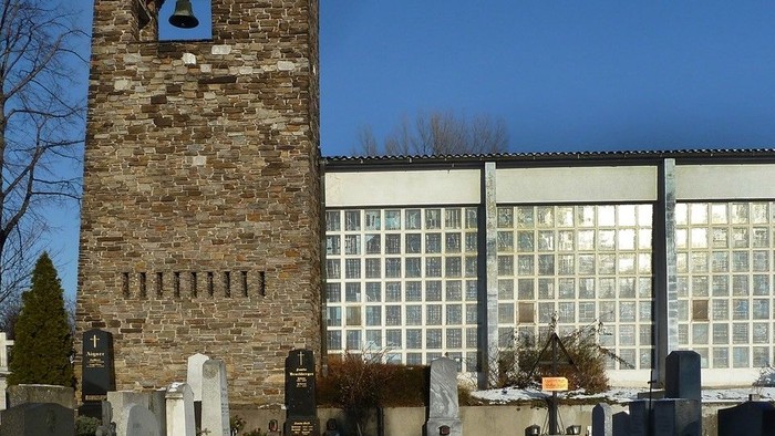 Alter Kirchturm neben moderner Kirche im Schnee