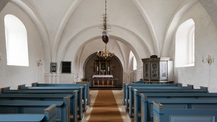 Indre del af kirke med blå bænke og hængende lygte