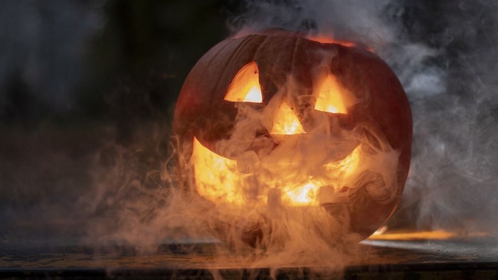 En glowende pumpkarl med røg omkring i mørke omgivelser