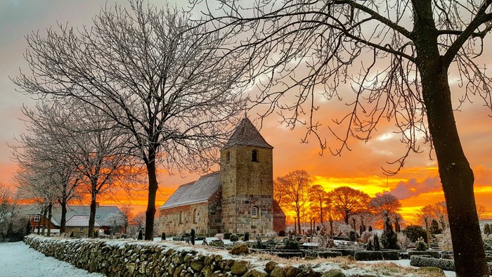 En kirke i sne og solopgang