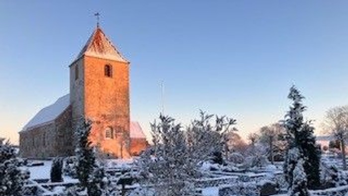 En kirke med tårn og klokke i snefuld landskab