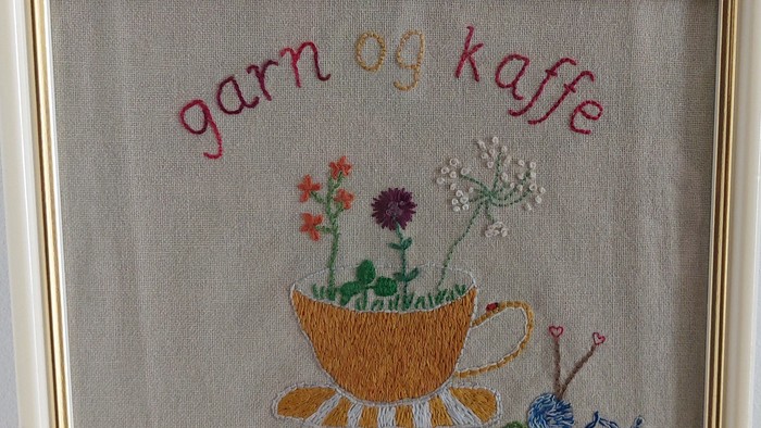 Håndbroderet tekop med blomster, garn og teksten