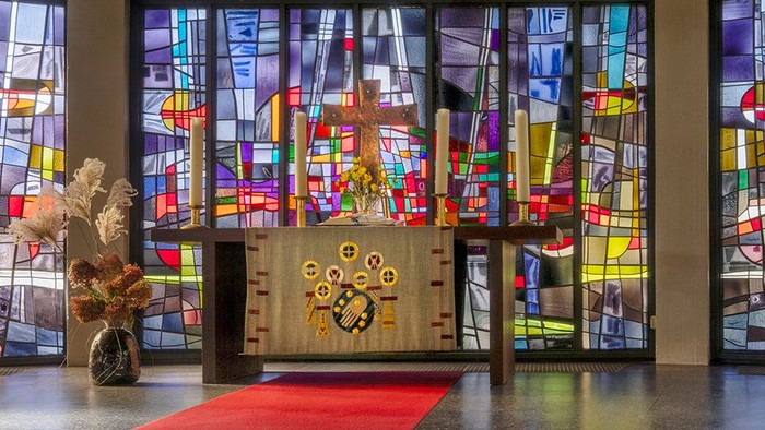 Kircheninneres mit Buntglasfenstern und rotem Teppichgang