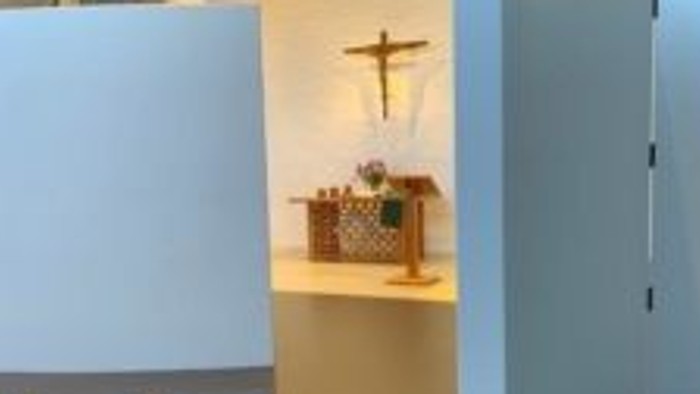 Moderne Kircheninnenraum mit weißen Wänden und hölzernem Kruzifix.