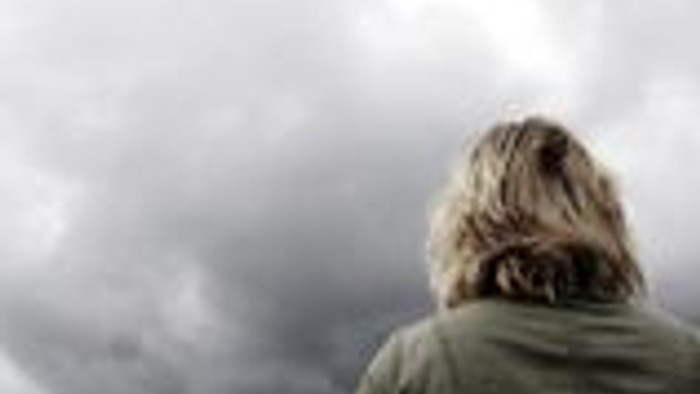 Eine Person steht unter einem bewölkten Himmel und blickt nach oben.