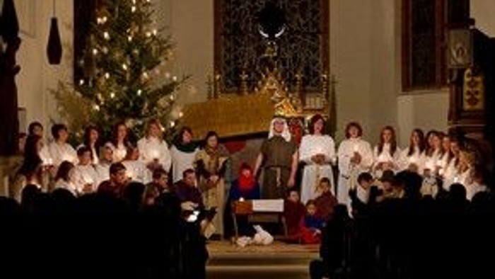 In der Kirche singt ein Kinderchor vor Weihnachtsbaum und Altar.