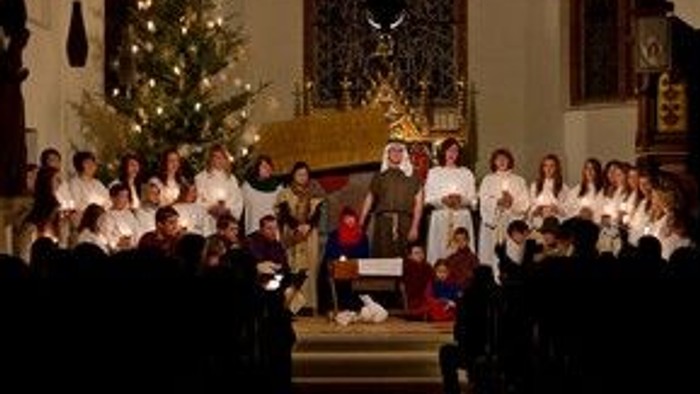 In der Kirche singt ein Kinderchor vor Weihnachtsbaum und Altar.