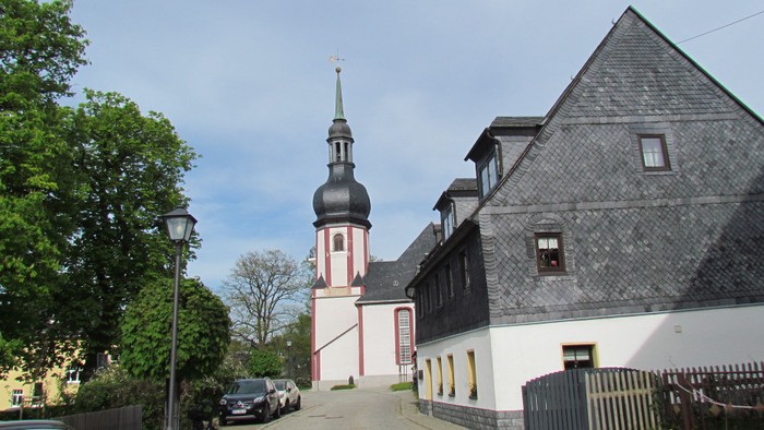 Kirchengemeinde mit hohem Turm und parkenden Autos