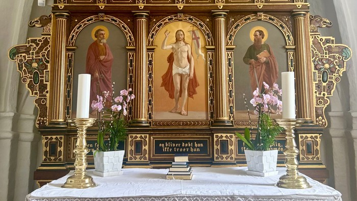 Elegant alter med religiøse statuer, lys, og prægtige gyldne udskæringer med blomsterdekorationer.