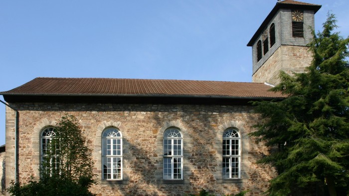 Außenansicht der evangelischen Kirche in Oedelsheim. Natursteingebäude mit roten Ziegeldach.