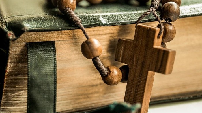 Holzkreuz und Rosenkranz auf einem Buch