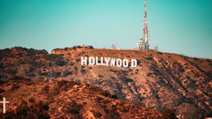 Det ikoniske Hollywood-skilt placeret på en bjergside under en klar blå himmel.