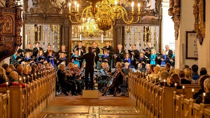 En kirke med kor og orkester under optræden, mens forsamlingen sidder i bænkene.