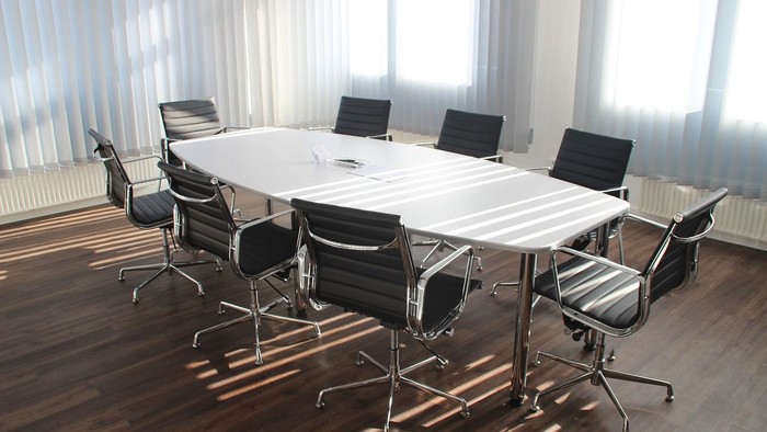 Ein moderner Konferenzraum mit einem großen Tisch und acht schwarzen Stühlen.