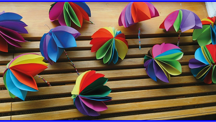 Bunte Papierblumen auf Holzboden.