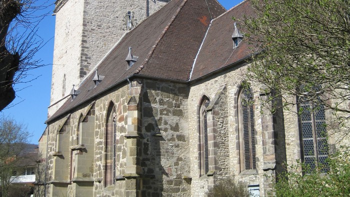 Außenansicht der evangelischen Stadtkirche in Zierenberg von Süden. Natursteingebäude mit hohen Spitzbogenfenstern und großem Turm mit geschwungener Dachhaube.