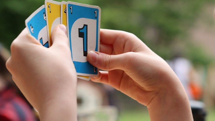 Person, die im Freien eine Spielkarte mit der Nummer eins hochhält.