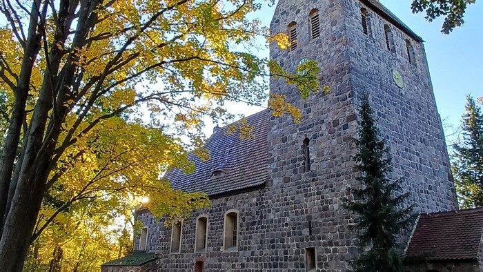 Dorfkirche Marienfelde umgeben von Bäumen mit Herbstlaub