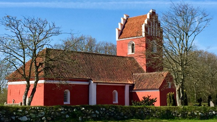 Rødt kirke med tårn og tagtegn i træ.