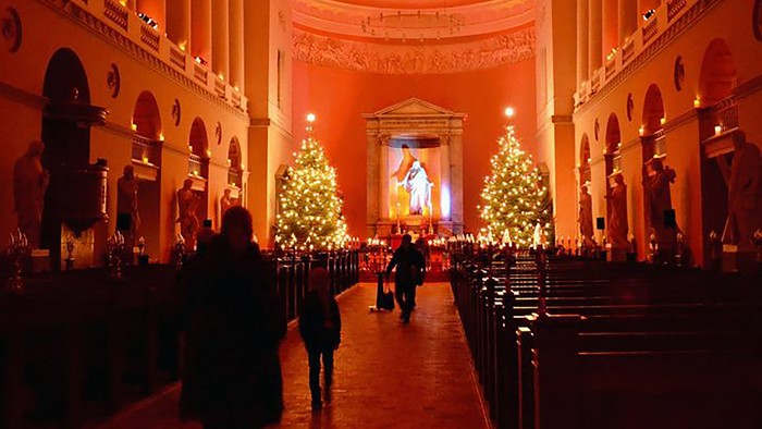 Indre del af en stor kirke med julestænder og besøgende.